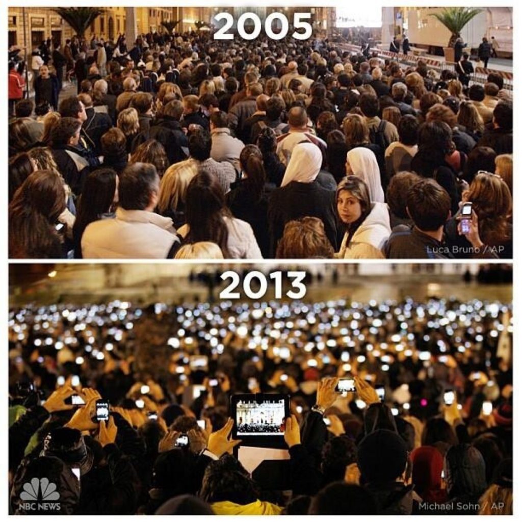 Two crowds experiencing an event. 2005 with no phones, 2013 shows everyone recording or taking a photo on their phone or tablet.