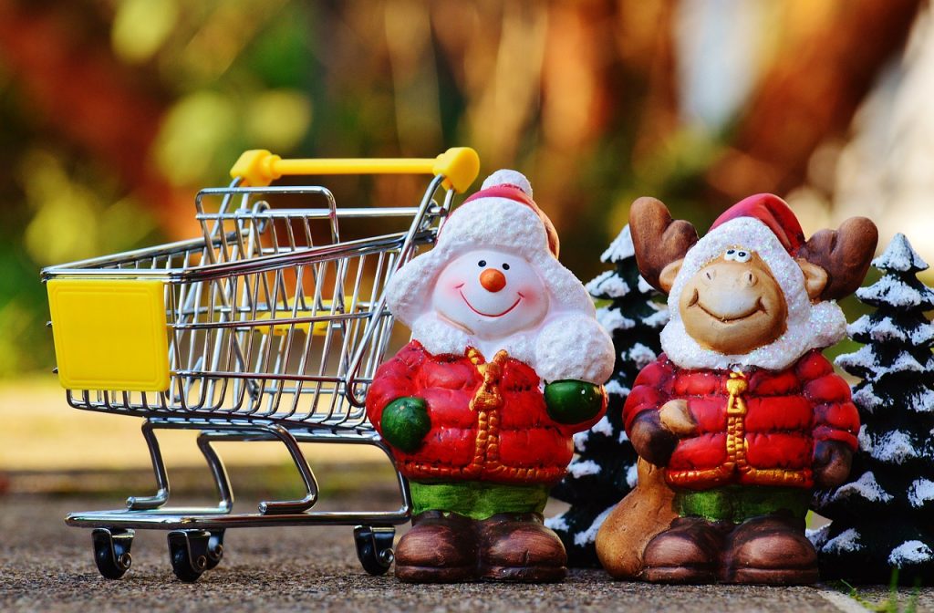 2 christmas trees and statues next to a shopping cart