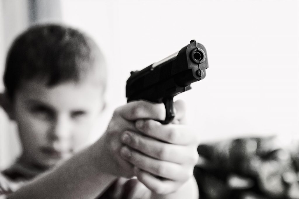 Child holding and aiming pistol