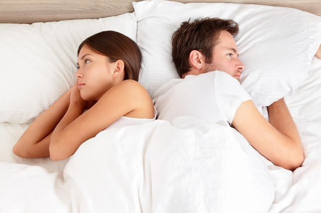 Photo of couple in bed facing away from each other