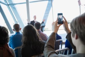 Woman photographing politician with camera phone at rally